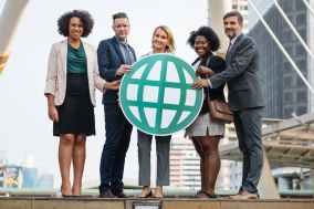 five people standing while holding green globe art