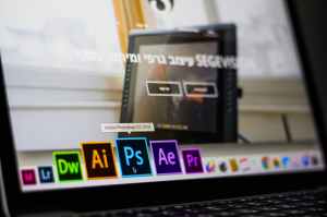 turned on laptop on desktop with hovered adobe photoshop cc application